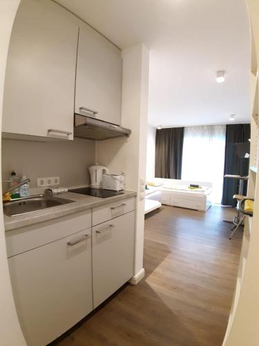 a kitchen with white cabinets and a wooden floor at LEA-Apartments Zentrum Ost mit Stellplatz in Leipzig