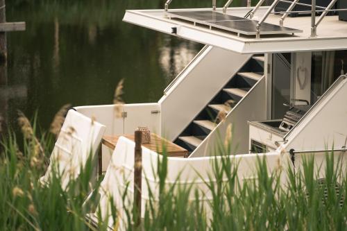 德米茨Deine schwimmende Auszeit auf dem Wasser -Festlieger Hausboot Tobago的船上的椅子坐在水边