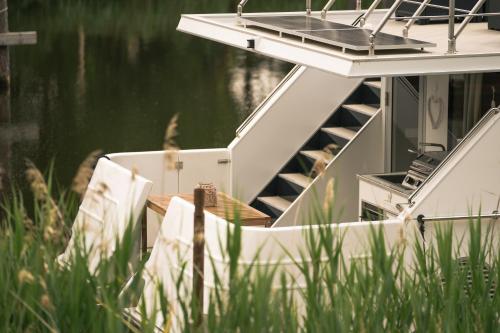 a boat with chairs sitting on the side of the water at Deine schwimmende Auszeit auf dem Wasser -Festlieger Hausboot Tobago in Dömitz