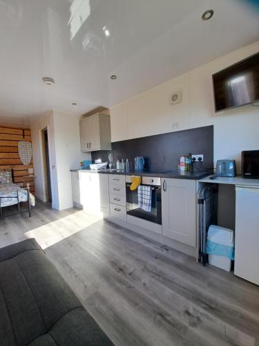 a large kitchen with white cabinets and a couch at The Posh Bothy Spean Bridge in Roybridge