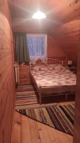 ein Schlafzimmer mit einem Bett in einer Holzhütte in der Unterkunft Wynajem pokoi Burniszki in Wiżajny