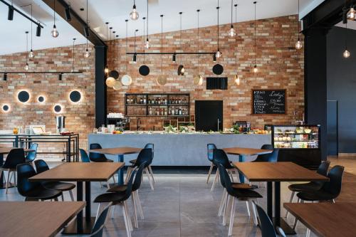 a restaurant with wooden tables and chairs and a brick wall at Wiartel Osrodek Wypoczynkowy in Pisz