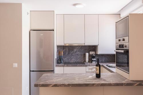 a kitchen with white cabinets and a bottle of wine on a counter at Apartamentos Martalia Áticos Deluxe in Ronda