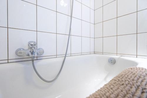 a shower in a white tiled bathroom with a tub at Le Jardin du vieux moulin 6b in Rendeux