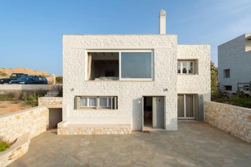 a white brick house with a large window at Villa Alkinoi in Kampos Paros