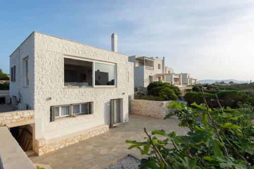 a white brick house with a large window at Villa Alkinoi in Kampos Paros