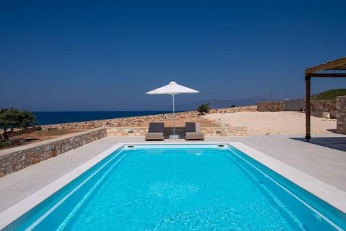 a swimming pool with two chairs and an umbrella at Villa Alkinoi in Kampos Paros