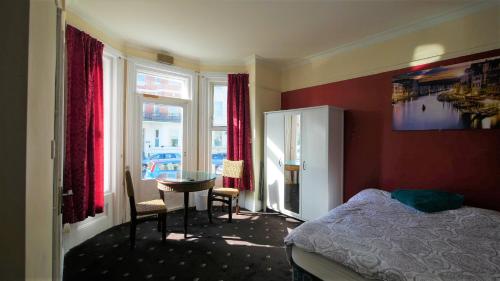 a bedroom with a bed and a table and a window at Palm Beach Hotel in Bournemouth