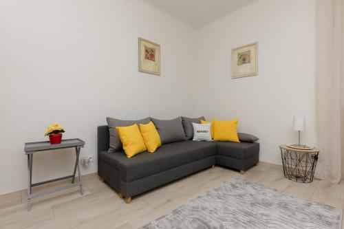 a living room with a gray couch with yellow pillows at Racławicka Cozy Studio Apartment by Renters in Warsaw