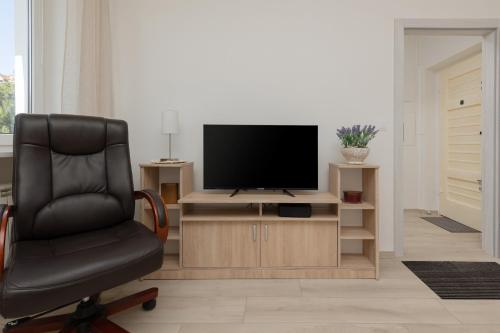 a living room with a chair and a television at Racławicka Cozy Studio Apartment by Renters in Warsaw