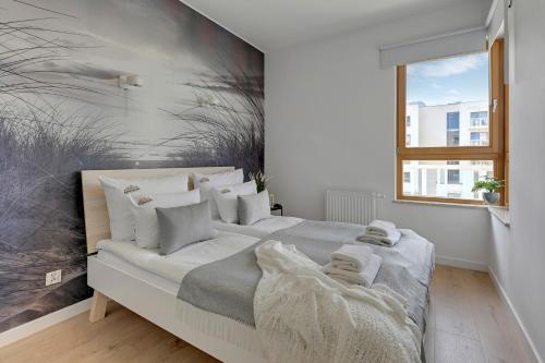 - une chambre blanche avec un grand lit et des oreillers blancs dans l'établissement Downtown Apartments Seaside Mila Baltica - Sauna, Gym & Parking, à Gdańsk