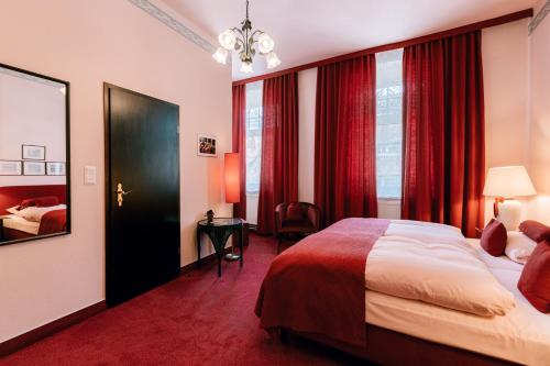 Habitación de hotel con cama y cortinas rojas en Hotel Der Schwan en Einbeck