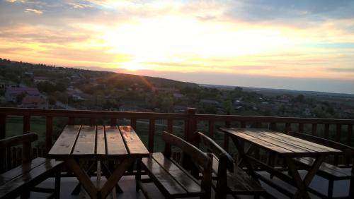 una mesa de madera y sillas en un balcón con vistas a la puesta de sol en MINERI CAZARE, en Tulcea