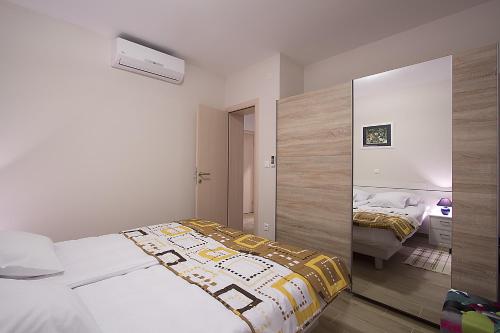 a white bedroom with a bed and a mirror at Apartments Ragusa Palace 1 Djardin in Dubrovnik