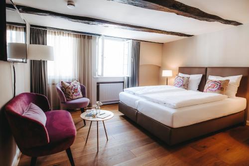 een hotelkamer met een bed en twee stoelen bij Hotel zum Heidkrug & Café Lil in Lüneburg