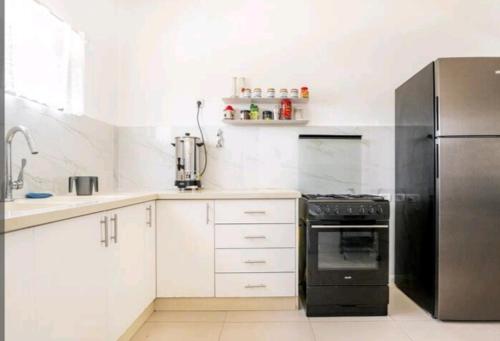 a kitchen with white cabinets and a black refrigerator at אחוזת מלכי ישראל לשומרי שבת וכשרות in H̱osen