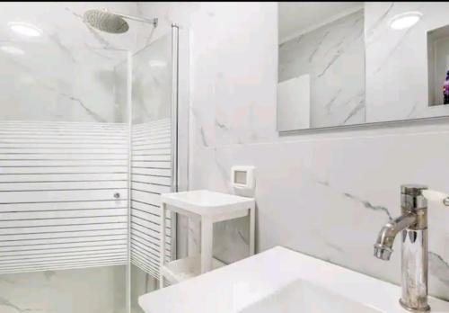 a white bathroom with a sink and a shower at אחוזת מלכי ישראל לשומרי שבת וכשרות in H̱osen