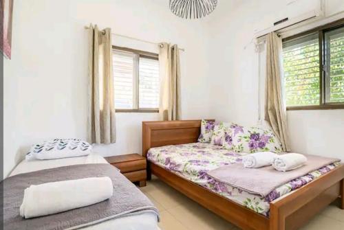 a bedroom with two beds and two windows at אחוזת מלכי ישראל לשומרי שבת וכשרות in H̱osen