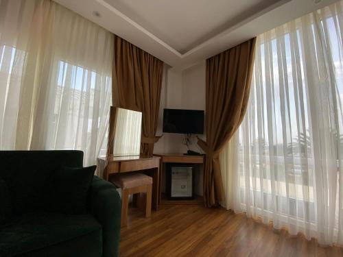 a living room with a couch and a tv and windows at ASKAR PORT OTEL in Tasucu
