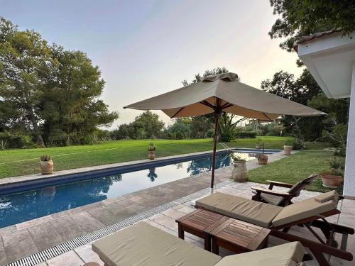 Villa avec piscine privée في طبرقة: وجود مظله وكراسي بجانب مسبح