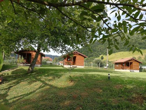 two small wooden buildings in a field with a tree at Căsuțe Zăvoi Bulz in Bulz