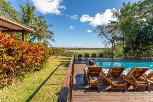 St Lucia的住宿－Sunset Lodge，一个带椅子的甲板和一个游泳池