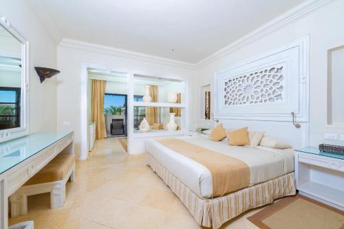 a white bedroom with a large bed and a desk at The Makadi Spa Hotel - Couples Only 18 Years Plus in Hurghada