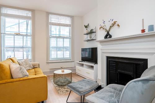 a living room with a yellow couch and a fireplace at Stylish 1 bed flats in Soho, next to Piccadilly Circus and Trafalgar Square in London