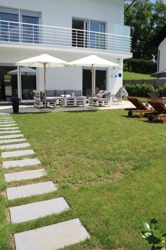 une maison dotée d'une pelouse avec des chaises et des parasols dans l'établissement Landhaus Anton, 