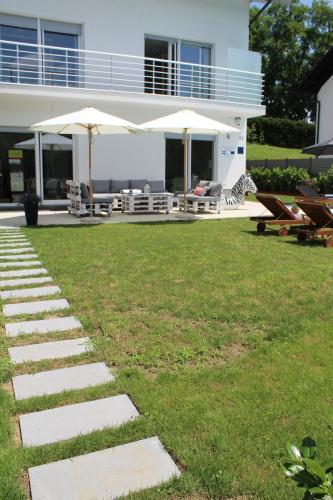 a house with a lawn with chairs and umbrellas at Landhaus Anton in Žakanje