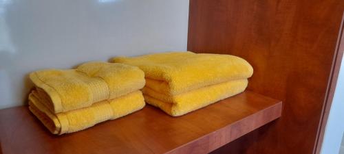 una pila de toallas amarillas en una estantería de madera en Coco Lux Studio Grand Baie, en Grand Baie
