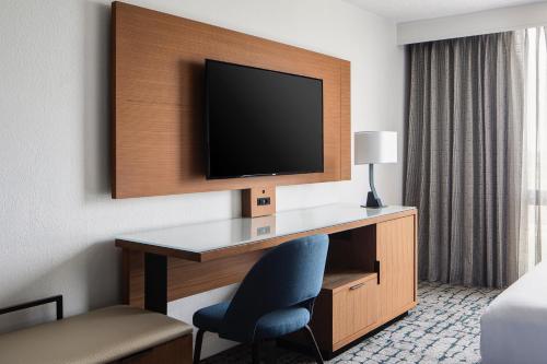 a hotel room with a desk with a tv and a chair at Houston Marriott South at Hobby Airport in Houston