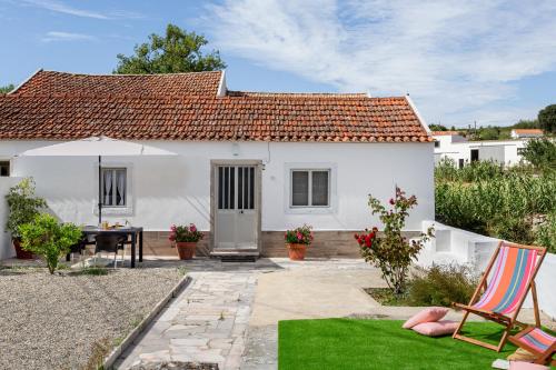 ein weißes Haus mit einem Tisch und einer Liegewiese in der Unterkunft ALTIDO Quaint house with Patio in Sintra