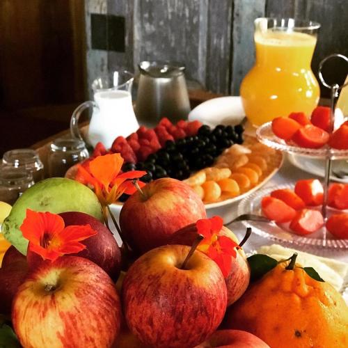 a table with apples oranges and other fruits on it at A Casa Vermelha Hospedaria in Tiradentes