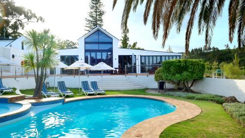 ein Haus mit einem Pool und Palmen in der Unterkunft Houw Hoek Hotel in Botrivier