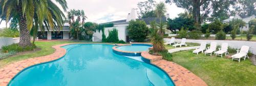 a swimming pool in a yard with chairs and a house at Houw Hoek Hotel in Botrivier