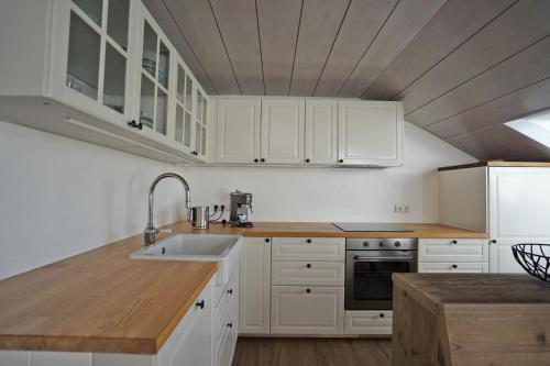 eine Küche mit weißen Schränken und einem Waschbecken in der Unterkunft Allgäuer Hideaway in Oy-Mittelberg