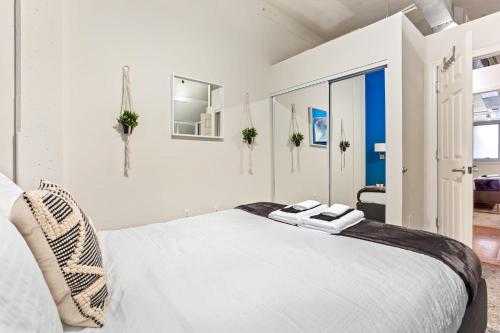 a white bedroom with a bed and a mirror at Downtown Durham 2BR Apt Walk Everywhere & Wifi in Durham
