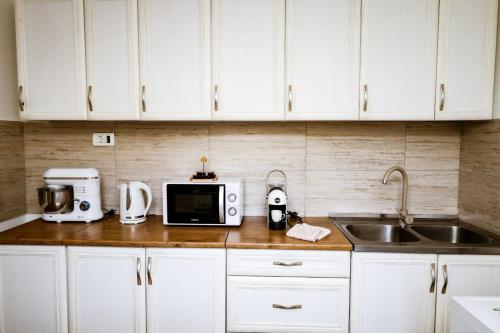 een keuken met witte kasten, een wastafel en een magnetron bij Apartment Nada Smodlaka in Tivat