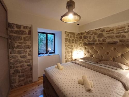 een slaapkamer met een bed met een stenen muur bij Apartment Nada Smodlaka in Tivat