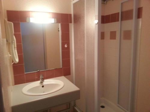 a bathroom with a sink and a shower with a mirror at Résidence des 3 Césars in Aulus-les-Bains