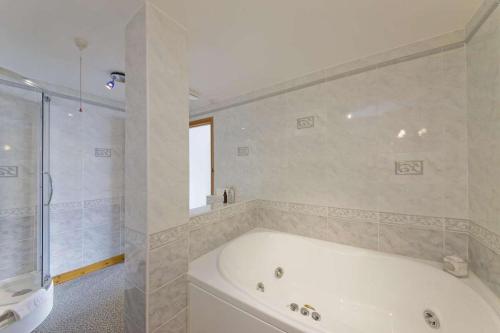 a white bathroom with a tub and a shower at Esplanade Court Holiday Apartments in Oban