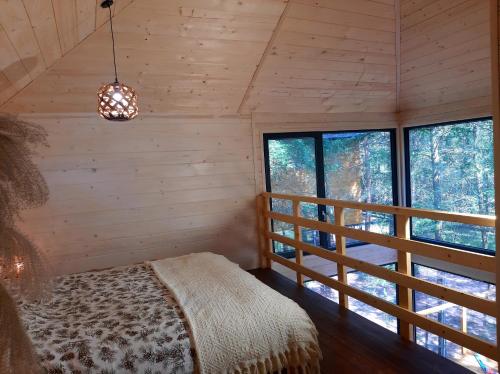 a bedroom in a log cabin with a bed and windows at Wood Land Liswarta domki w drzewach in Popów