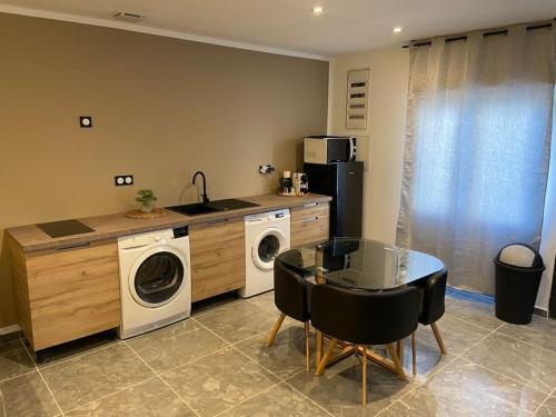 a kitchen with a washing machine and a table with chairs at Maison avec jacuzzi in Orange