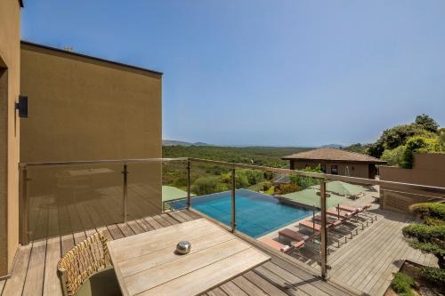 a house with a deck and a swimming pool at Hôtel Version Maquis Santa Manza in Bonifacio