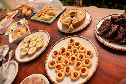 una mesa cubierta con platos de repostería y postres en Cocco Pousada en Maragogi