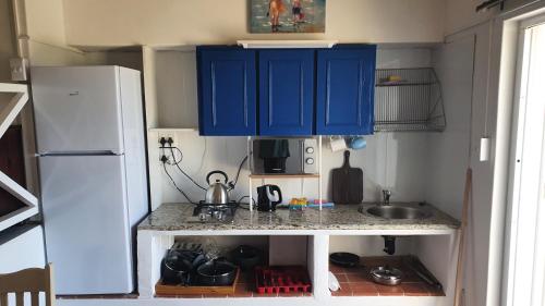 cocina pequeña con armarios azules y nevera blanca en Ocean Walk Marlin, en Zinkwazi Beach