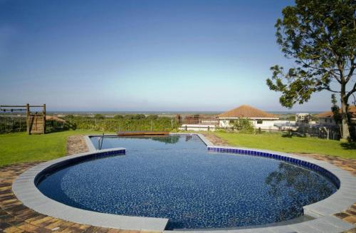 a large swimming pool in a yard with a tree at Sara's Upmarket Apartment - Lagoon Views, Patio, Braai & WIFI & DSTV in Plettenberg Bay