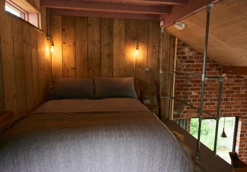 uma cama num quarto com uma parede de tijolos em The Tiny House em Shootend