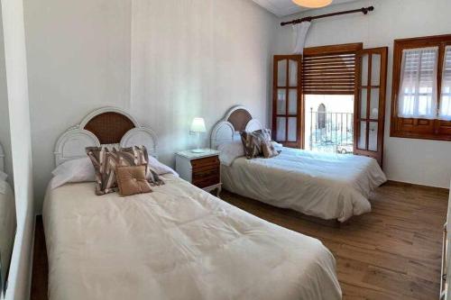 two beds in a room with white walls and wooden floors at El Balcón de La Rosa in La Puebla de Montalbán